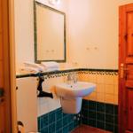 Badezimmer mit Waschbecken, Spiegel, Toilette und Handtuchhalter.
