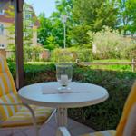 Terrasse mit Stuhl und Tisch, Blick auf grünen Garten und Häuser.