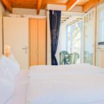 Schlafzimmer mit Doppelbett, Kleiderschrank und Blick auf Balkon.