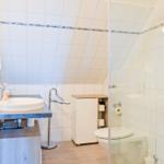 Badezimmer mit Dusche, Toilette und Waschbecken unter Dachschrägen.