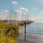 Hafen mit Segelbooten und ruhigem Wasser unter blauem Himmel.