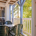 Terrasse mit Tisch und Stühlen, Blick auf Bäume und blauen Pfosten.