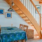 Esszimmer mit Holztreppe und Tisch mit blauem Tischtuch.