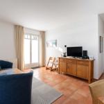 Wohnzimmer mit Sofa, Fernseher und Terrassentür.