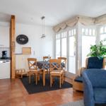 Küche, Essbereich und Wohnbereich mit blauen Sesseln und Holzmöbeln.