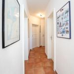 Flur mit Terrakottaboden und Wandbildern an den Wänden.