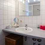 Badezimmer mit Waschbecken, Spiegel und Dusche