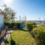 Terrasse mit Tisch und Stühlen, Blick auf Hafen mit Booten.