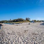 Strand mit Sand, Wellen und Menschen in der Ferne