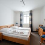 Ein Schlafzimmer mit einem Doppelbett, einem Schreibtisch und einem Fenster.