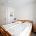 Schlafzimmer mit Doppelbett, zwei Nachttischen und einer Tür.