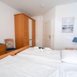 Schlafzimmer mit Doppelbett, Kleiderschrank und Bildern an den Wänden.