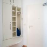 Eingangsbereich mit weißem Schrank und Tür. Blaue Tasche im Schrank.