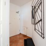 Flur mit Terrakottboden, Heizkörper und Wandgarderobe.