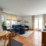 Wohn- und Essbereich mit Sofa, Stühlen und Fenstern.