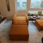 Orange Sofa und Sitzbank im Wohnzimmer mit Holzboden und Fenster.
