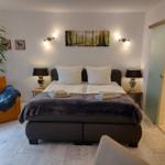 Schlafzimmer mit Bett, Nachttischen und Wandbild. Anschlussbad sichtbar.