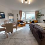 Ein Raum mit Schlaf- und Essbereich, zwei Sesseln und einem großen Fenster.