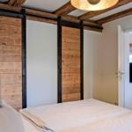 Schlafzimmer mit Holzpaneelen und Bett. Durchgang zur Küche sichtbar.