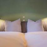 Doppelbett mit Kissen und Wandlampen an grünem Wand