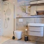 Dusche mit Glaswand, Waschbecken und Toilette in moderner Badezimmerausstattung.