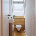 Badezimmer mit Toilette, Waschbecken und Dachfenster.