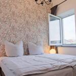 Schlafzimmer mit Bett, Fenster und floraler Tapete.