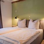 Schlafzimmer mit Doppelbett, grüner Wand und zwei Wandlampen.