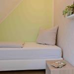 Ein Bett mit Kissen und Bettwäsche unter einer schrägen Decke. Wand mit Muster und Nachttisch.