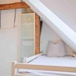 Schlafzimmer mit Dachschrägen, weißem Bett und Holzkonstruktion.