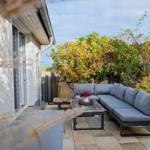 Terrasse mit Sitzgruppe, Tisch und Pflanzen im Herbst.