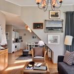 Wohnzimmer mit Sofa, Sessel und Küchenbereich unter Treppe