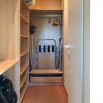 Ein Kleiderschrank mit Regalen, Kleiderständer und einem Rollator.