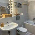 Badezimmer mit Badewanne, Waschbecken und Toilette. Wandbild und Segelschiffmodell.