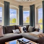 Wohnzimmer mit Sofa, Kissen und Blick auf Außen