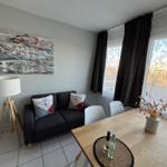 Wohn- und Essbereich mit Sofa, Tisch und Fenster.