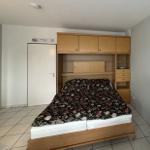 Schlafzimmer mit Bett und Holzmöbeln, Tür und Fliesenboden