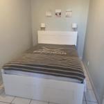 Schlafzimmer mit weißem Bett und gestreifter Bettdecke.