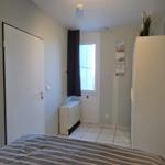 Schlafzimmer mit Bett, Kleiderschrank und Fenster mit Vorhang.