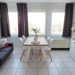 Wohn- und Essbereich mit Sofa, Esstisch und Fernseher.