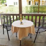 Terrasse mit runden Tisch, zwei Stühlen und Flasche Champagner.
