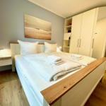 Schlafzimmer mit Doppelbett, Kleiderschrank und Wandbild.