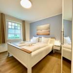 Schlafzimmer mit Bett, Fenster und Wandbild.