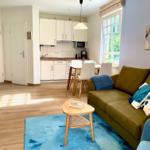 Wohnzimmer mit Sofa, Tisch und Küche im Hintergrund.