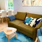 Ein Wohnzimmer mit Sofa, Tisch und Blauem Teppich.