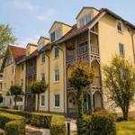 Gelbes Mehrfamilienhaus mit Balkonen und gepflegtem Garten.