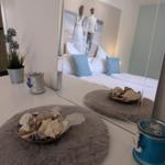 Schlafzimmer mit Spiegel, Stranddeko und Bett im Hintergrund.