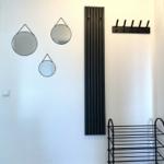 Wand mit drei runden Spiegeln, Heizkörper und Garderobe