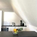 Küche mit Schranksystem, Spüle und Kochfeld unter schrägem Dach