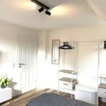 Schlafzimmer mit Bett, Kleiderschränken, Fernseher und Pflanze.